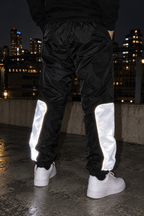 Paneles reflectivos traseros de los joggers CHOMPITER brillando de noche con sneakers blancos