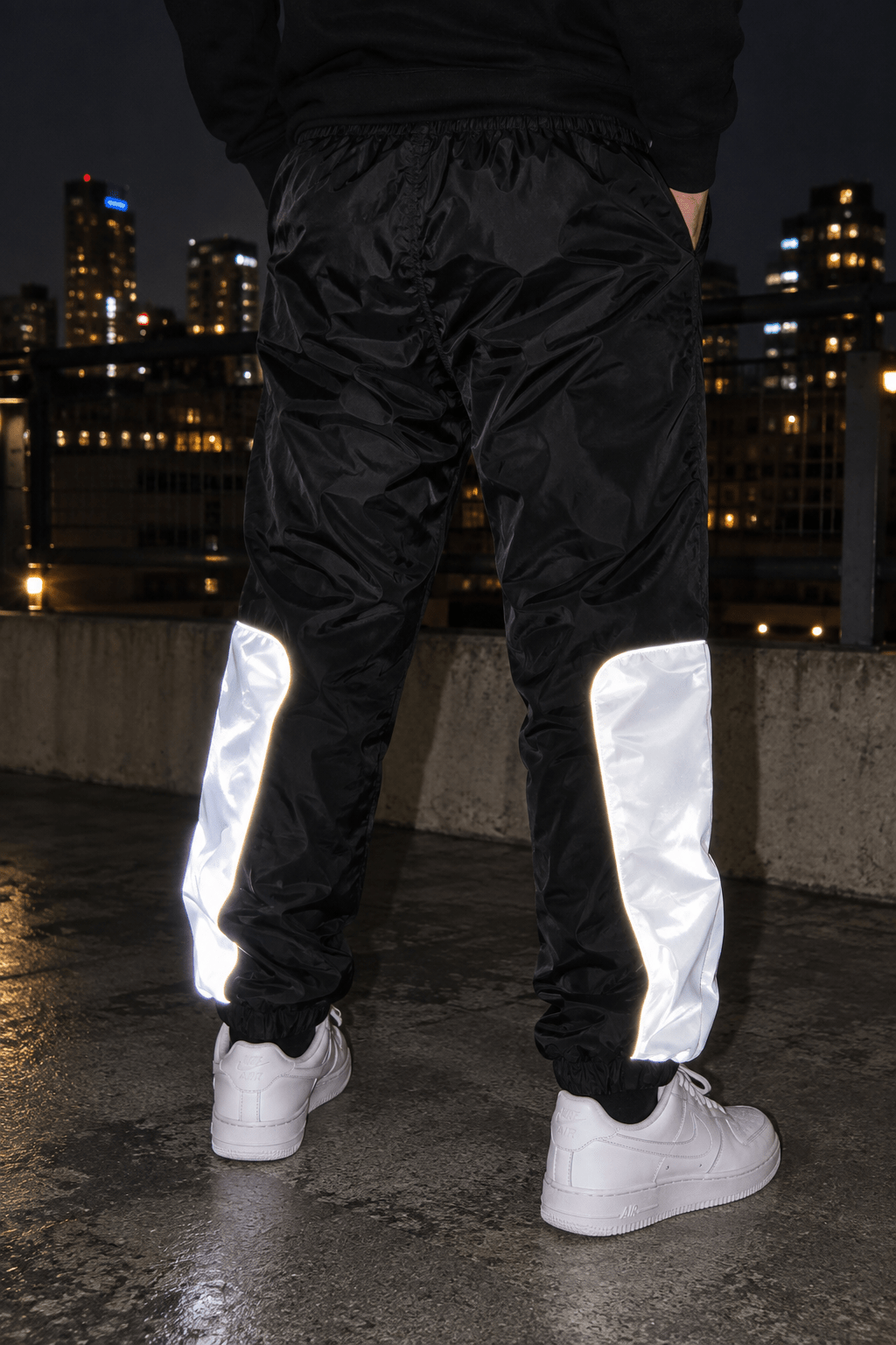 Paneles reflectivos traseros de los joggers CHOMPITER brillando de noche con sneakers blancos